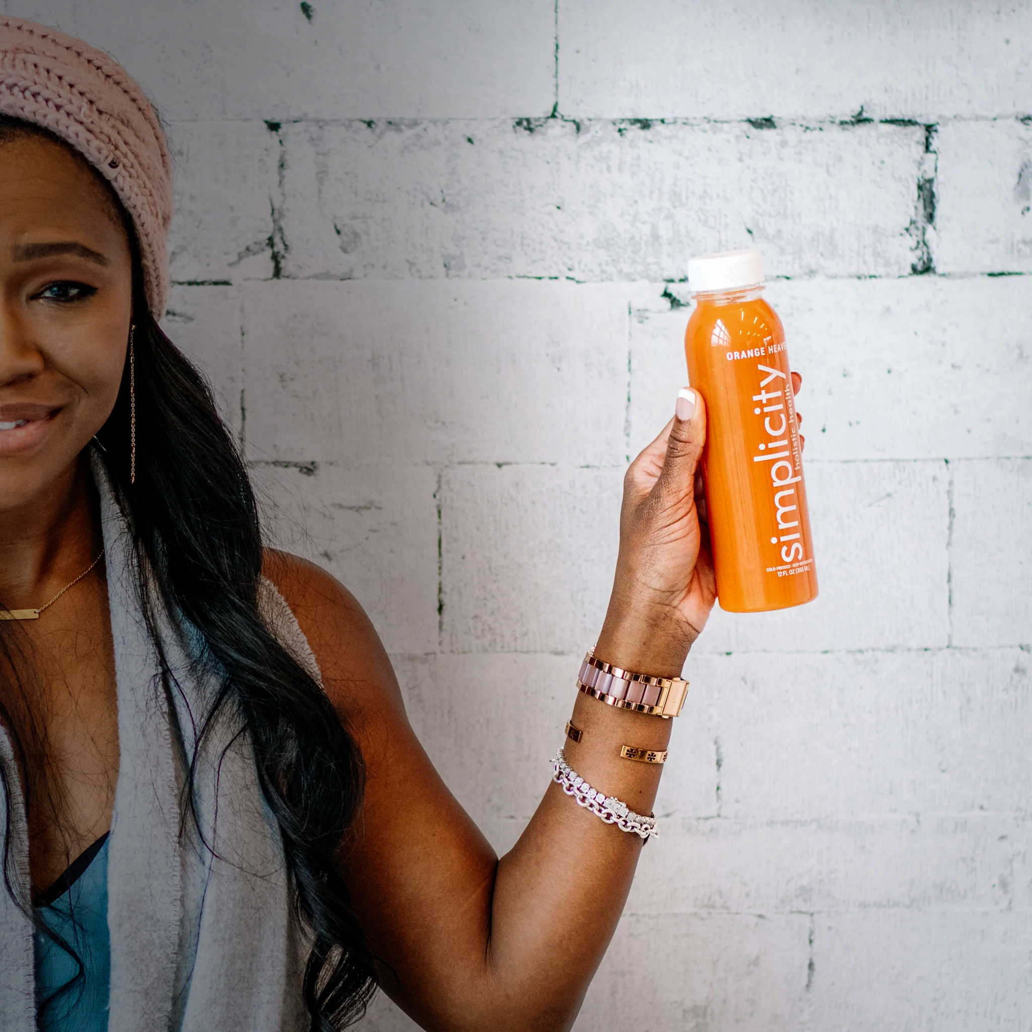 Beautiful woman holding a bottle of Simplicity Cold Pressed Orange Heaven Juice.